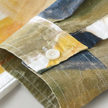 Detail of the buttoned cuff in olive and ochre tones.