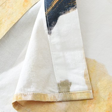 Detail of the shirt hem and side seam in ivory and warm ochre.