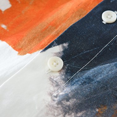 The button placket, where a burnt orange stroke meets charcoal.